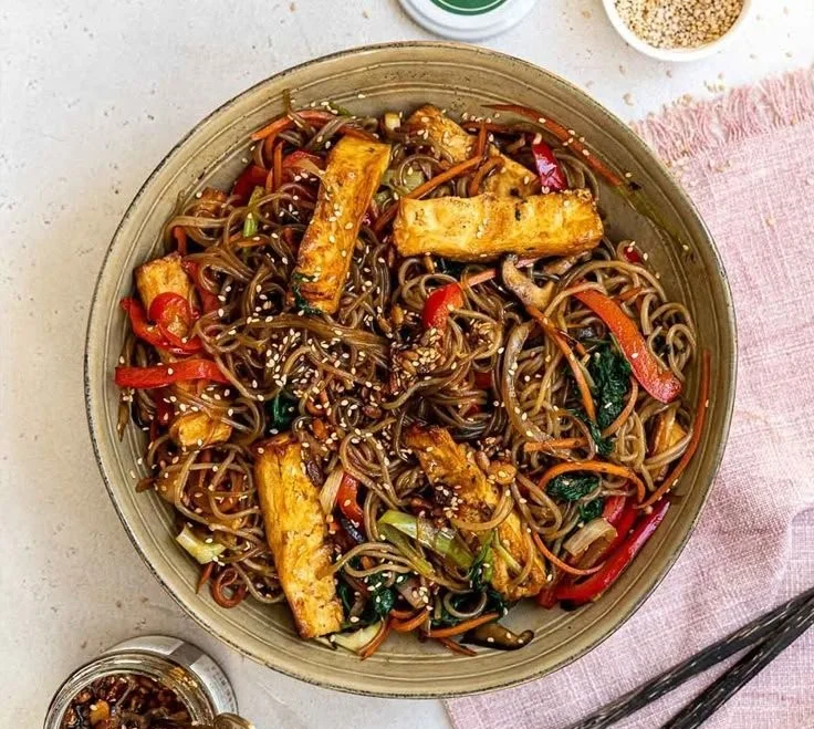 Veganes Japchae mit buntem Gemüse und Glasnudeln, serviert in einer Schüssel.