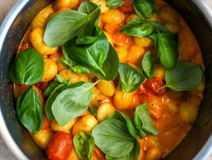 Einfache cremige Gnocchi serviert auf einem Teller mit frischen Kräutern.