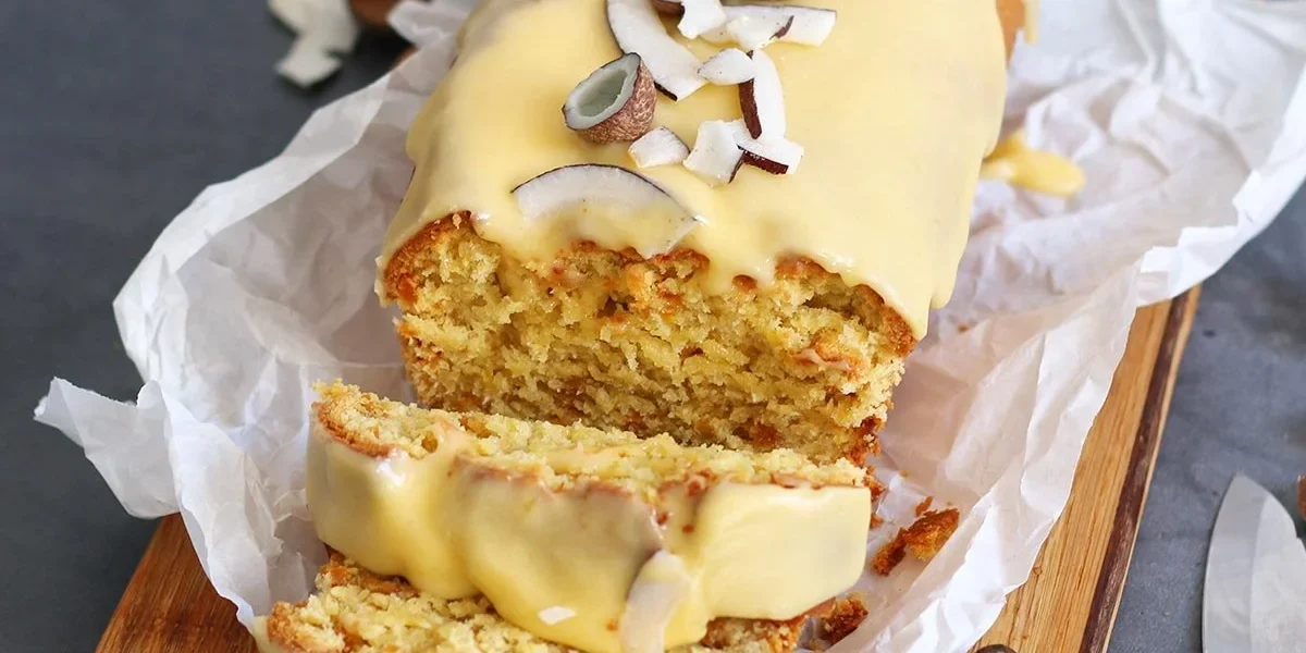 Einfacher Mango Kokosnuss Kastenkuchen auf einem Teller, dekoriert mit frischen Mangostücken.