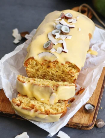 Einfacher Mango Kokosnuss Kastenkuchen auf einem Teller, dekoriert mit frischen Mangostücken.