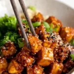 Knoblauch-Sesam-Tofu mit frischen Zutaten auf einem Teller