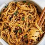 Schüssel mit Knoblauch-Sesamnudeln, garniert mit Sesam und Frühlingszwiebeln