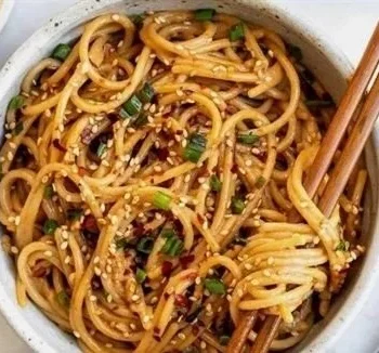 Schüssel mit Knoblauch-Sesamnudeln, garniert mit Sesam und Frühlingszwiebeln