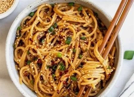 Schüssel mit Knoblauch-Sesamnudeln, garniert mit Sesam und Frühlingszwiebeln