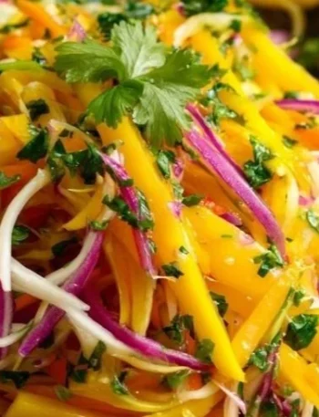 Bunte Schüssel mit Mango Slaw, garniert mit frischen Kräutern und Limetten.