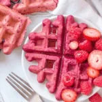 Vegane Rote Beete Waffeln auf einem Teller, dekoriert mit frischen Früchten.
