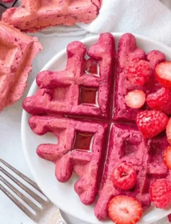 Vegane Rote Beete Waffeln auf einem Teller, dekoriert mit frischen Früchten.