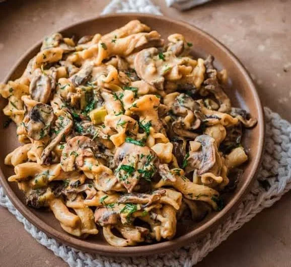 Veganes Pilz-Stroganoff Gericht auf einem Teller mit frischen Kräutern