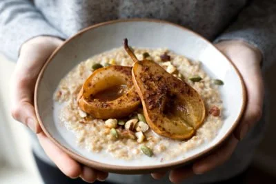 Schüssel mit veganem Porridge mit Früchten und Nüssen garniert