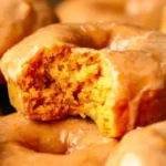 Vegane Kürbisdonuts auf einem Teller, dekoriert mit Zuckerguss