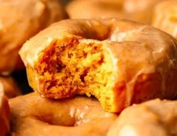 Vegane Kürbisdonuts auf einem Teller, dekoriert mit Zuckerguss