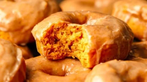 Vegane Kürbisdonuts auf einem Teller, dekoriert mit Zuckerguss