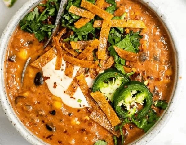 Schüssel mit veganer Tortilla-Suppe mit Gemüse und knusprigen Tortilla-Streifen