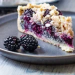 Veganer Streuselkuchen mit Brombeeren und Mohn auf einem Tisch serviert.