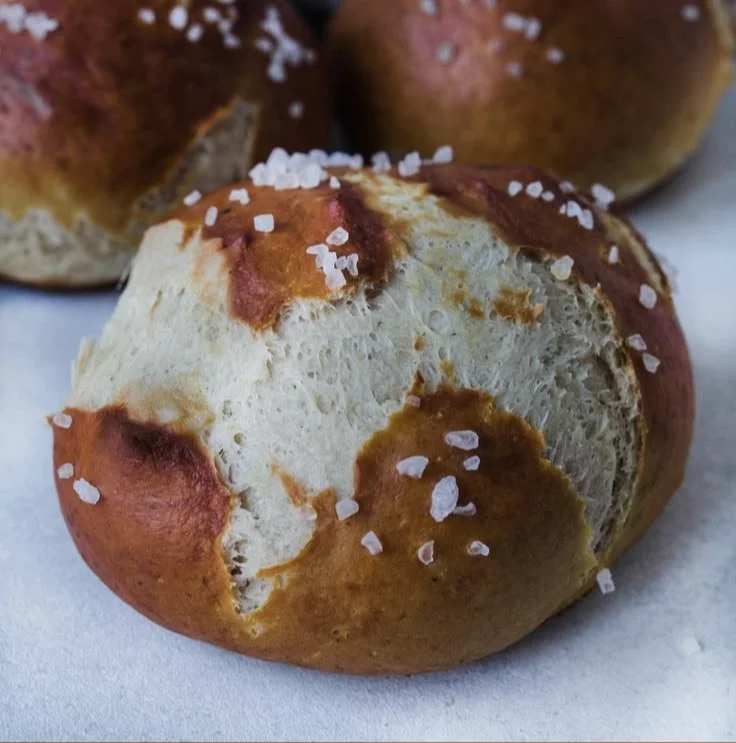 Frisch gebackene weiche Brezelbrötchen auf einem Holzbrett
