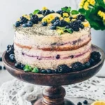 Vegan Zitronen-Mohn-Torte auf einem eleganten Teller, garniert mit Zitronenscheiben.