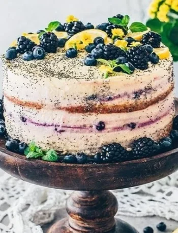 Vegan Zitronen-Mohn-Torte auf einem eleganten Teller, garniert mit Zitronenscheiben.