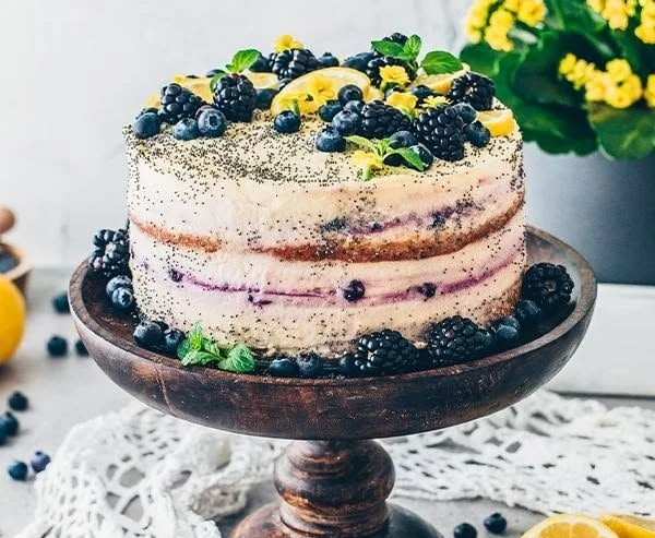 Vegan Zitronen-Mohn-Torte auf einem eleganten Teller, garniert mit Zitronenscheiben.