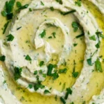 Zitronen- und Kräuter-Weißbohnendip in einer Schüssel, serviert mit frischem Brot.