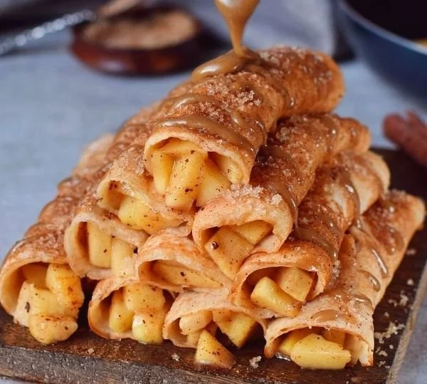 Leckere Apfel-Zimt-Crepes auf einem Teller, garniert mit Äpfeln und Zimt.