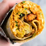 Leckeres veganes Frühstücks-Burrito mit frischem Gemüse und Tofu.