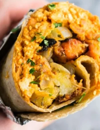 Leckeres veganes Frühstücks-Burrito mit frischem Gemüse und Tofu.
