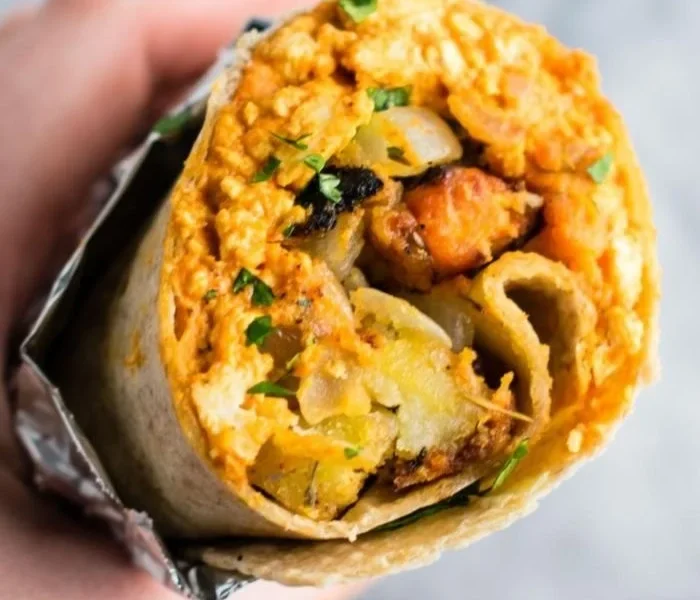 Leckeres veganes Frühstücks-Burrito mit frischem Gemüse und Tofu.