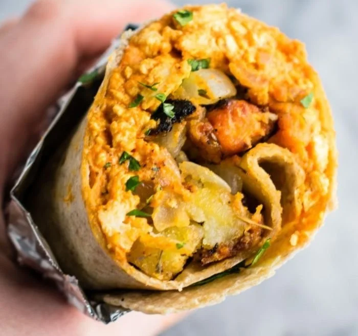 Leckeres veganes Frühstücks-Burrito mit frischem Gemüse und Tofu.