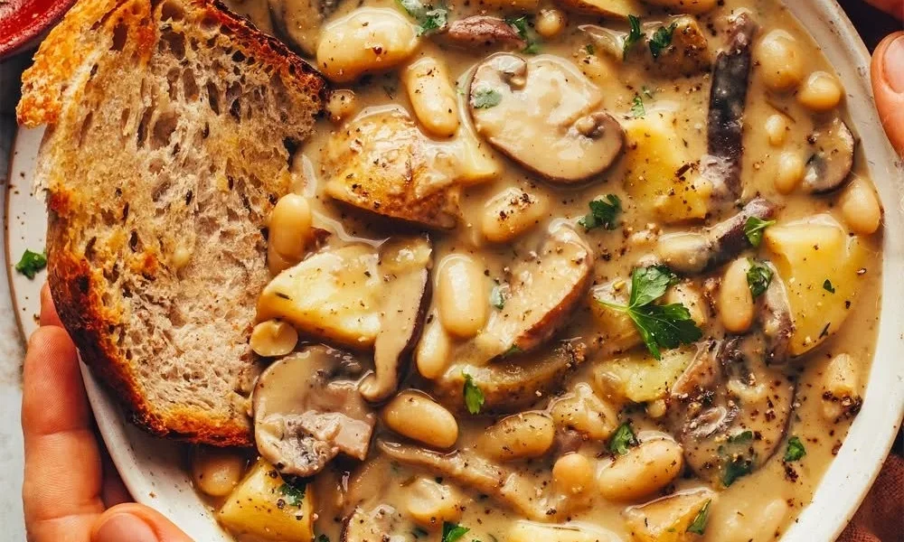 Cremige weiße Bohnensuppe mit Pilzen in einer Schüssel serviert.
