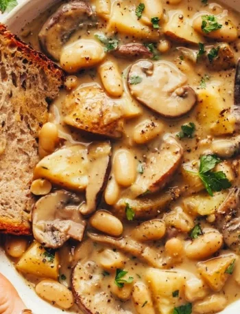 Cremige weiße Bohnensuppe mit Pilzen in einer Schüssel serviert.