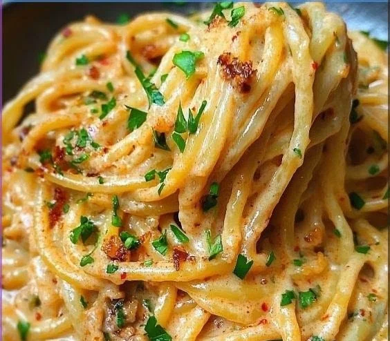 Cremige vegane Pasta mit karamellisierten Zwiebeln auf einem Teller serviert.