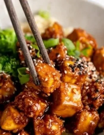 Knuspriger gebackener Sesam-Tofu auf einem Teller mit frischen Kräutern