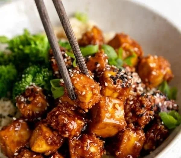 Knuspriger gebackener Sesam-Tofu auf einem Teller mit frischen Kräutern