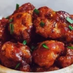 Veganes General Tso's Blumenkohl serviert mit Reis und Sesam