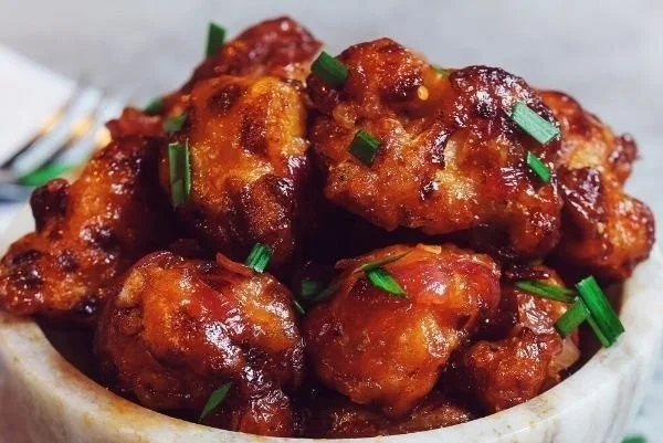 Veganes General Tso's Blumenkohl serviert mit Reis und Sesam
