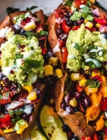 Vegane gefüllte Süßkartoffeln mit buntem Gemüse und Kräutern auf einem Teller.