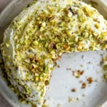 Karotten-Pistazienkuchen auf einem Teller mit frischem Obst dekoriert