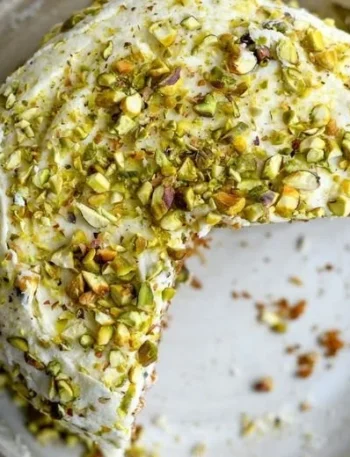 Karotten-Pistazienkuchen auf einem Teller mit frischem Obst dekoriert