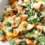 Würzige Kartoffel-Kohl-Schalen mit Senf-Tahini-Dressing auf einem Teller