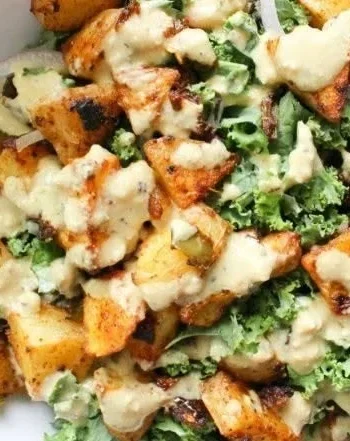 Würzige Kartoffel-Kohl-Schalen mit Senf-Tahini-Dressing auf einem Teller