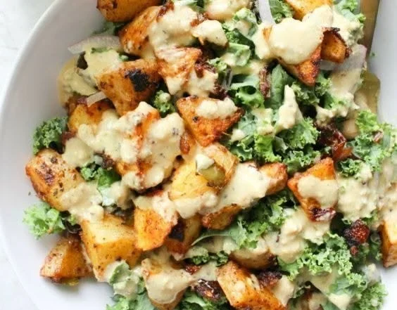 Würzige Kartoffel-Kohl-Schalen mit Senf-Tahini-Dressing auf einem Teller