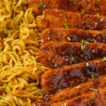Sweet and Spicy Tempeh mit Knoblauch-Curry-Nudeln auf einem Teller serviert
