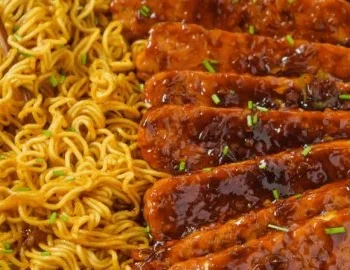 Sweet and Spicy Tempeh mit Knoblauch-Curry-Nudeln auf einem Teller serviert