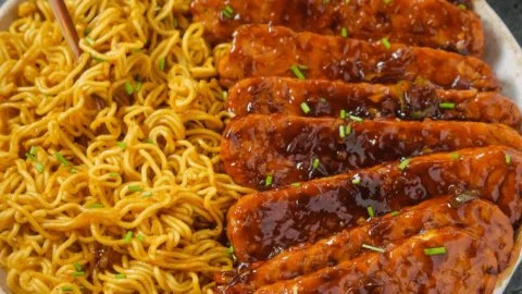 Sweet and Spicy Tempeh mit Knoblauch-Curry-Nudeln auf einem Teller serviert