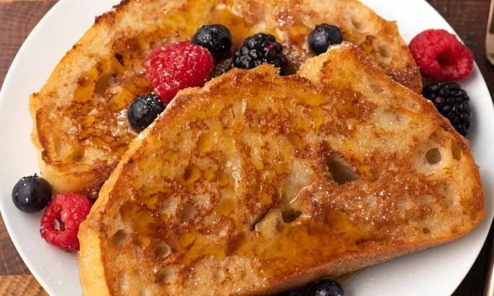 Veganer French Toast mit frischen Bananen und Ahornsirup serviert.