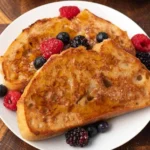 Veganer French Toast mit frischen Bananen und Ahornsirup serviert.