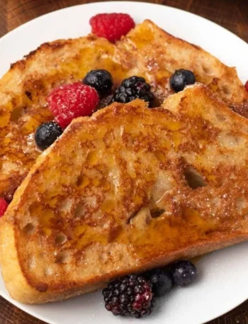 Veganer French Toast mit frischen Bananen und Ahornsirup serviert.
