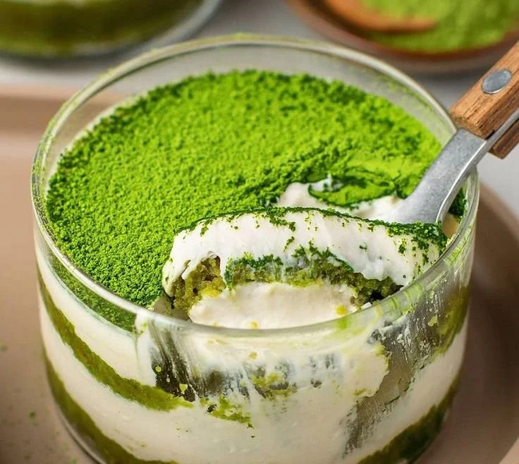 Veganer Matcha Tiramisu auf einem Teller mit grünem Matcha-Pulver dekoriert.